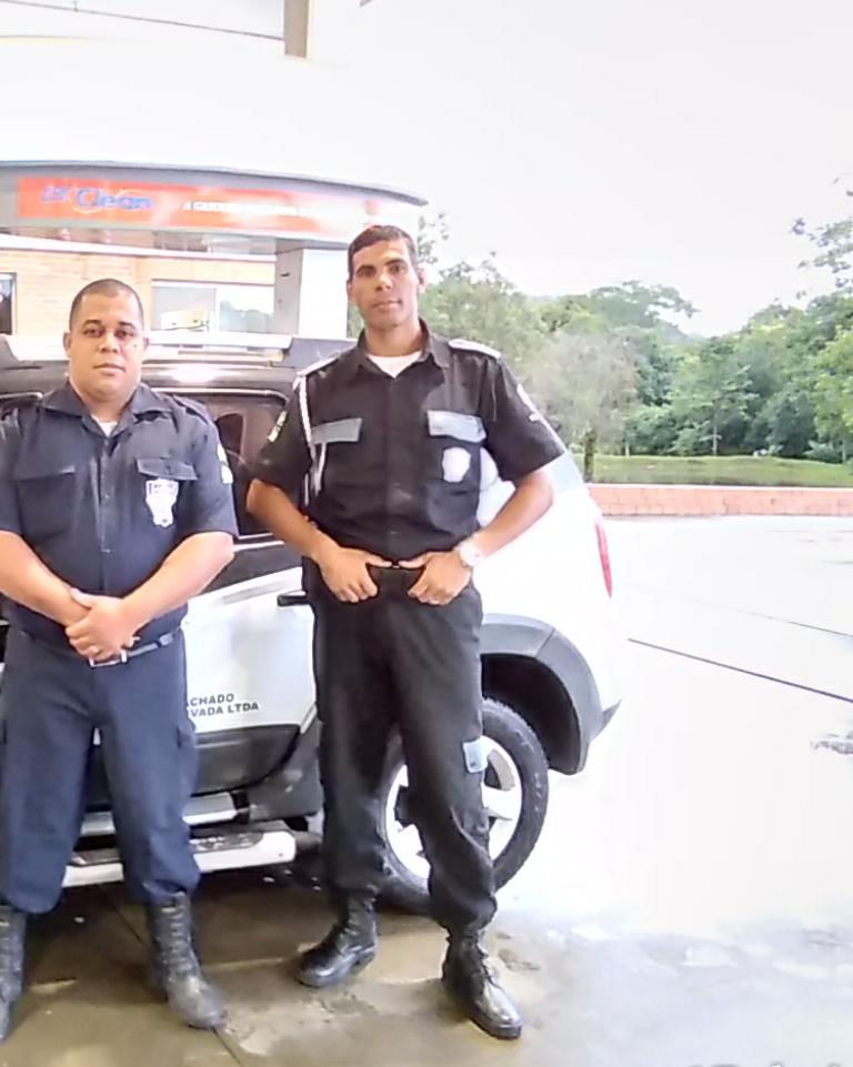 Dois vigilantes uniformizados da Pfeffer Machado ao lado da viatura 001